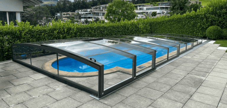 Schwimmbad mit transparenter Glasabdeckung im Garten.